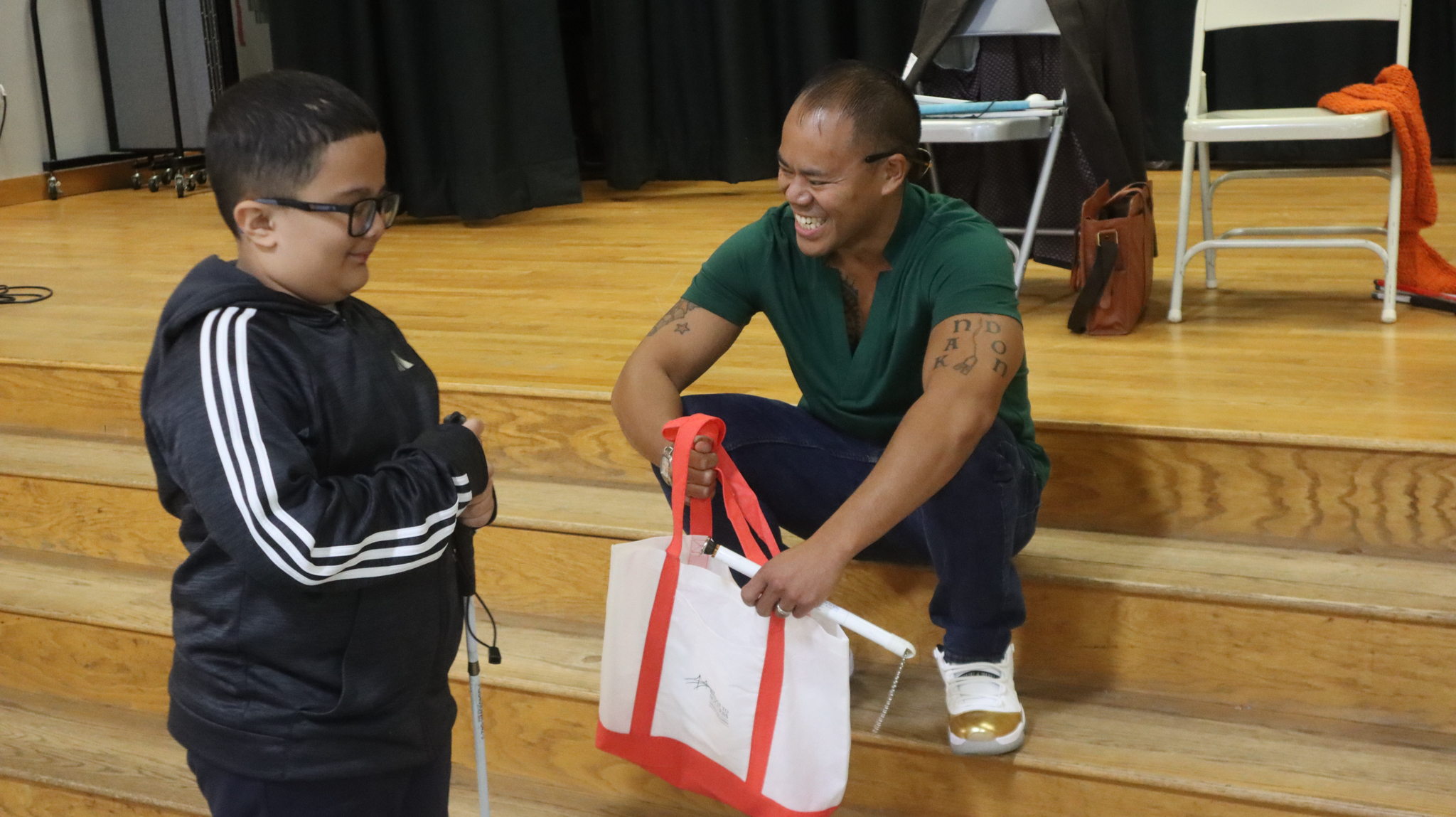 A Chelsea Public Schools student, presents Massachusetts Director of Programs and Services Joey Buizon with some CPS swag
